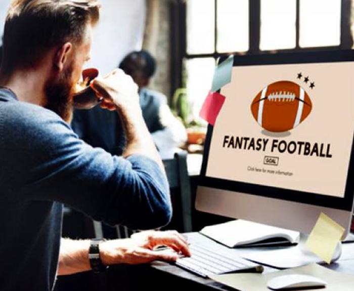 Man at a computer drinking coffee looking up Fantast Football